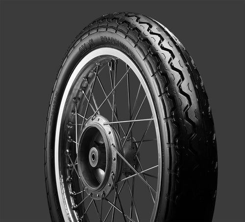 A black Avon Vintage and Classic Tire by Avon Tyres with a shiny silver rim shows a classic tread of thin parallel grooves on its circumference, set against a plain white background.