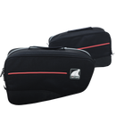 Two Ventura Bonneville travel bags in black with red accents and a logo on the side are featured. The front bag displays a zipper and top carrying handle, while the rear bag appears slightly blurred. Both bags showcase a sleek, modern design.