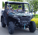 A rugged black Ventura CF Moto U10 Pro Highland is parked outdoors, featuring large tires, bull-bars, a front guard, two seats with headrests, and a winch on the bumper. Its towbar suggests hauling capability. Trees and grass surround the scene.
