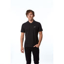 A person with short hair wears an Alpinestars Capital Polo Black from ALPINESTARS, featuring a small logo and classic 2-button design, paired with black pants against a plain white background.
