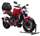 The image shows a Ventura EVO-12 Bike-Pack Kit on a Ducati 821 Monster (14-16). The sleek black pack features an orange stripe, an adjustable EVO-Rack attached to the bike, and is completed by an L-Bracket with screws. Each component is labeled for easy identification.