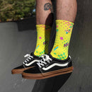 A pair of AEROBIX FLUORO YELLOW SOCKS with various colorful patterns, including pink and green geometric shapes, checkerboard designs, and zigzag lines. Crafted from super soft cotton, they feature targeted arch compression for added support and the brand name "FIST" near the top. The toes are solid yellow.