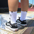 WHITE STOCKER SOCKS by FIST: white cotton crew socks with a black fist logo on the ankle, black text on the sole, and arch compression for support, shown on a plain white background.