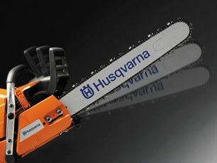 A Husqvarna 3120 XP-2838® Chainsaw featuring a powerful long metallic cutting blade with a chain, an orange body, and a black handle. The brand name "Husqvarna" is prominently displayed on the blade, embodying the power and reliability needed for maintaining lawns and other outdoor tasks.