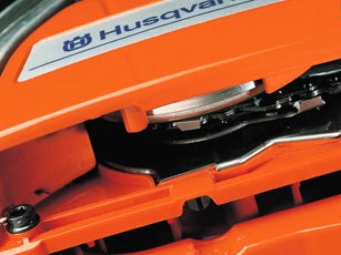 A Husqvarna 3120 XP-2838® Chainsaw featuring a powerful long metallic cutting blade with a chain, an orange body, and a black handle. The brand name "Husqvarna" is prominently displayed on the blade, embodying the power and reliability needed for maintaining lawns and other outdoor tasks.