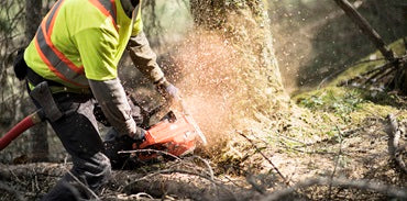 A Husqvarna 572 XP-24® Chainsaw with an orange body and a long metal cutting bar is perfect for all your outdoor needs. Shown from the side, it proudly displays the "Husqvarna" brand on the bar, along with intricate details of the engine and handle.