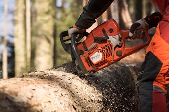 A Husqvarna 572 XP-24® Chainsaw with an orange body and a long metal cutting bar is perfect for all your outdoor needs. Shown from the side, it proudly displays the "Husqvarna" brand on the bar, along with intricate details of the engine and handle.