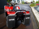 A Ventura Honda TRX 520 FA5 (20 - >) quad bike with black accents, silver bull-bars, and a rugged mud flap is parked on a paved road beside green shrubs and grass.