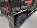 A Ventura Honda Pioneer 1000-5P in red and black, featuring roll bars and rugged tires, is parked on a paved area before a large industrial building with a corrugated metal facade.