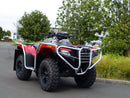 The Ventura Honda TRX 700 FA ATV, featuring bull-bars, a tow-ball, large rugged tires, and a protective metal frame in red and black, is parked on a paved road with trees and a building visible in the background.