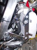 Close-up of the Radiator Frame by Emperor Racing, featuring metal and plastic components with hoses and a side tank. The metal sports an "Emperor Racing" logo.