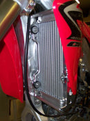 Close-up of the Radiator Frame by Emperor Racing, featuring metal and plastic components with hoses and a side tank. The metal sports an "Emperor Racing" logo.