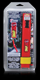 A person uses a Snapjack from Tirox to stabilize the rear tire of a motorcycle with a red wheel cleaning stand, keeping it lifted for maintenance on a concrete surface, with a partial building view in the background.