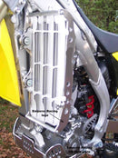 Close-up of the Radiator Frame by Emperor Racing, featuring metal and plastic components with hoses and a side tank. The metal sports an "Emperor Racing" logo.