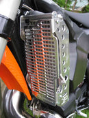 Close-up of the Radiator Frame by Emperor Racing, featuring metal and plastic components with hoses and a side tank. The metal sports an "Emperor Racing" logo.