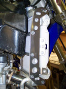 Close-up of the Radiator Frame by Emperor Racing, featuring metal and plastic components with hoses and a side tank. The metal sports an "Emperor Racing" logo.