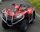 A Ventura Kymco MXU 400 (21 ->) ATV with large off-road tires and a silver bull bar is parked on pavement near green bushes and trees.