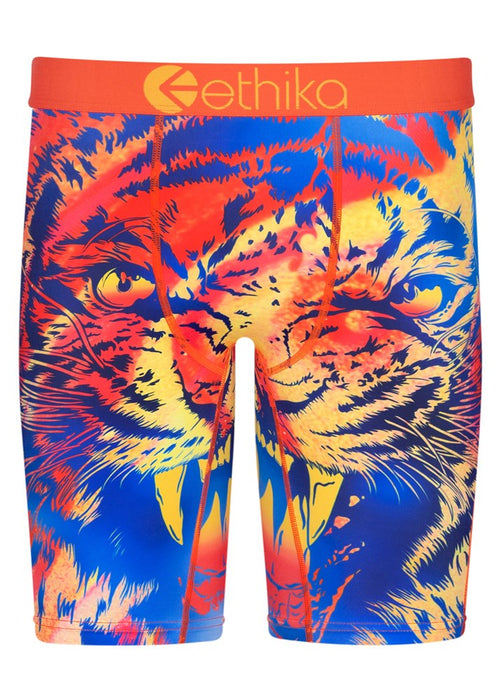 The image features the Ethika III Tiger Staple men's boxer briefs with a bold, graphic design showcasing a vibrant, fierce tiger face in shades of blue, orange, yellow, and red. The high-quality orange jacquard waistband prominently displays the brand name "ethika" in white letters.