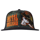 The Metal Mulisha Bunker Flex Hat is a black flat-brim cap with a multicolored camouflage design on the front panel and brim, featuring an embroidered skull icon in orange thread on the side panel, reflecting Metal Mulisha's signature style.