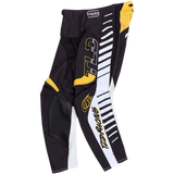The Troy Lee Designs GP PRO PANT FIFTY-50 BLACK / GOLD features black, white, and yellow graphic stripes, reinforced knee panels, "TLD" and "Troy Lee" branding, plus "TLD Racing" text along the leg. Pants are displayed flat on a white background.