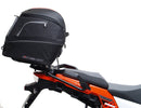 Ventura's EVO-12 Bike-Pack Kit image features a striking black EVO-12 pack with vibrant orange accents, an EVO-Rack gracefully fitted on a Suzuki DL 1050 V-Strom XT bike, and an L-Bracket with screws. The Adjustable Pack-Rack is designed to enhance your biking experience.