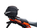 Ventura's EVO-12 Bike-Pack Kit image features a striking black EVO-12 pack with vibrant orange accents, an EVO-Rack gracefully fitted on a Suzuki DL 1050 V-Strom XT bike, and an L-Bracket with screws. The Adjustable Pack-Rack is designed to enhance your biking experience.