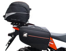 Ventura's EVO-12 Bike-Pack Kit image features a striking black EVO-12 pack with vibrant orange accents, an EVO-Rack gracefully fitted on a Suzuki DL 1050 V-Strom XT bike, and an L-Bracket with screws. The Adjustable Pack-Rack is designed to enhance your biking experience.