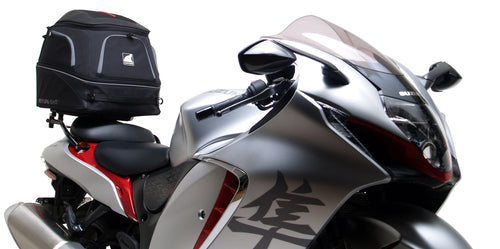 Image displaying a Ventura EVO-12 Bike-Pack Kit for Suzuki GSX 1300 R Hayabusa Gen III (21→), with a black EVO-12 pack, Evo-Rack Sport-Rack on the motorcycle, and labeled L-bracket with screws on a white background.
