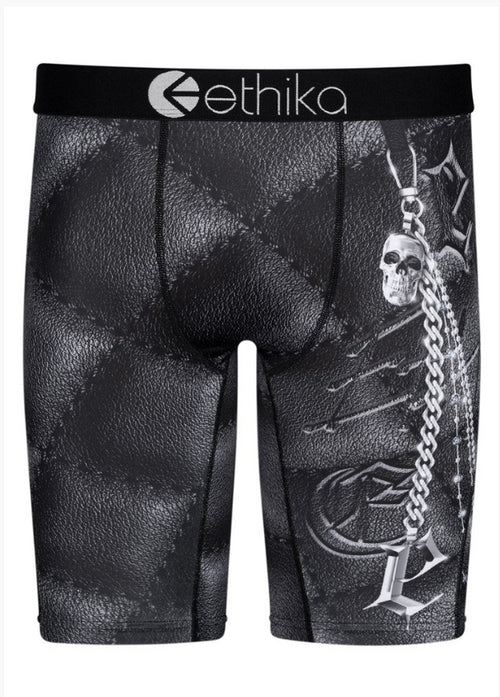 Ethika Chainbossed Staple boxer briefs, crafted by Ethika, showcase a black leather-like pattern and a detailed design of a skull, crossbones, and chain on the right leg. Made with original 4-way stretch fabric, they feature a high-quality waistband prominently displaying the Ethika logo at the center.