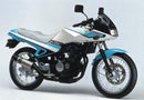Image showing the Ventura EVO-12 Bike-Pack Kit for Suzuki NZ 250 S (86-87), including an EVO-12 Pack (black bag), Evo-Rack (metal rack), and L-Bracket (black rods with mounting screws) for adjustable, secure mounting.