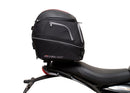 Image showing three components for the Ventura EVO-12 Bike-Pack Kit on a Triumph Scrambler 400X (24->): the EVO-12 pack (black bag), EVO-rack Sport-Rack (metal rack), and L-Bracket with hardware, each labeled with text.