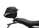 Image showing three components for the Ventura EVO-12 Bike-Pack Kit on a Triumph Scrambler 400X (24->): the EVO-12 pack (black bag), EVO-rack Sport-Rack (metal rack), and L-Bracket with hardware, each labeled with text.