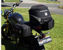 Image showing three components for the Ventura EVO-12 Bike-Pack Kit on a Triumph Scrambler 400X (24->): the EVO-12 pack (black bag), EVO-rack Sport-Rack (metal rack), and L-Bracket with hardware, each labeled with text.