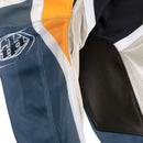 The Troy Lee Designs GP PRO AIR PANT BANDS DARK NAVY features bold geometric patterns in blue, white, black, yellow, and gray, with mesh polyester for ventilation, durable 600D polyester fabric, and a thigh logo.