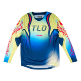 The Troy Lee Designs YOUTH GP PRO JERSEY DRIP GLO YELLOW/DARK NAVY is a long-sleeve motocross jersey with a blue, yellow, and white gradient, "TLD" chest logo, bold red/white sleeve graphics, and moisture-wicking fabric for comfort.