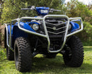 A blue Yamaha Kodiak 700 ATV, featuring a silver grille and bull bars, is parked on grass. It has large rugged tires amid trees and bushes. Under a clear sky, the vehicle by Ventura, equipped with mud flaps from the SE (16-17) series, faces slightly right.