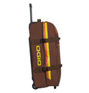 The OGIO TRUCKER Gear Bag - Stay Classy is a brown gear bag with an extended black handle, yellow and orange vertical stripes on the side, and a yellow OGIO logo. It is crafted from heavy-duty fabric, designed for carrying sports equipment, and features multiple straps and separate compartments.