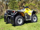 A Ventura Can-Am ATV Outlander G2 500 (12-13) in yellow with black and silver accents, sturdy bull-bars, a robust frame, and rugged tires is parked on grass amid greenery, designed for off-road adventures.