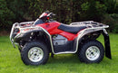 The Honda ATV TRX 680 FA (17-20) by Ventura, in red and black, is parked on green grass. It features sturdy metal racks front and back, bull-bars for added protection, large rugged tires, and a protective metal frame. Dense green foliage looms in the background.