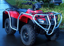 A red Ventura Honda ATV TRX 250 TE, TM (17 - >) with a personalized company logo and a silver front metal guard is parked on wet pavement. Green shrubs frame the background, while a car is partially visible on the right.