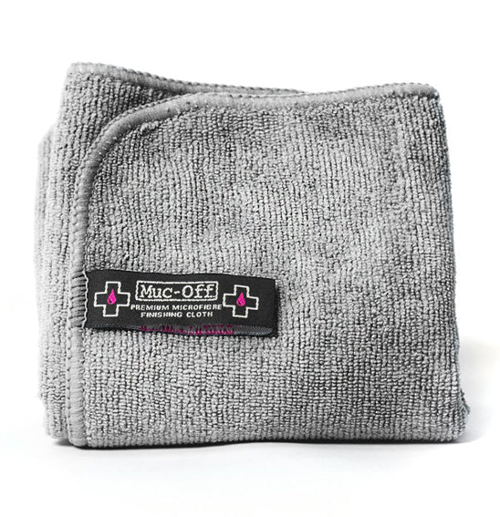 The Muc-Off Microfibre Polishing Cloth by MUC OFF features packaging with a striking black, white, and pink design adorned with a bold "X" and droplet icon. Ideal for helmets, visors, and goggles, it is crafted using advanced split-fibre technology to ensure it is both reusable and efficient. Plus, this cloth is machine washable.