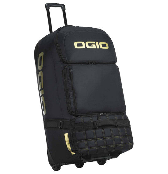 A large black OGIO Dozer Gearbag with a telescopic handle. It features the OGIO logo in yellow on the top flap and side. The bag has multiple zippered compartments, including a quilted front pocket and boot compartment for gear protection, and three sturdy wheels for easy transport.
