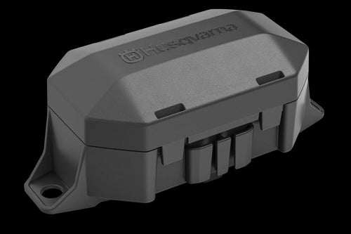 The Husqvarna Automower® Area Switch, enclosed in a gray plastic rectangular casing with a detachable cover, features the Husqvarna logo on top and includes various mounting points and connectors for electronic components. This shell is integral to the Husqvarna Automower, specifically designed to manage the boundary wire and Area Switch configurations.