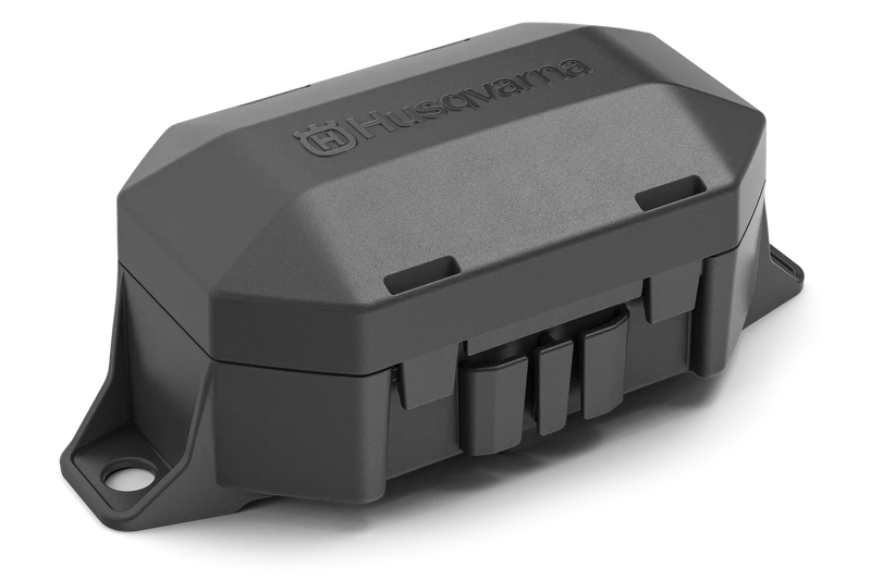 The Husqvarna Automower® Area Switch, enclosed in a gray plastic rectangular casing with a detachable cover, features the Husqvarna logo on top and includes various mounting points and connectors for electronic components. This shell is integral to the Husqvarna Automower, specifically designed to manage the boundary wire and Area Switch configurations.