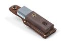 A Husqvarna Axe Grinding Stone, made of rectangular silicon carbide with a dual-color surface of grey and white, is placed next to a brown leather sheath featuring a snap button and stitched edges. The sheath, adorned with an embossed Husqvarna logo, stands out against the completely black background.