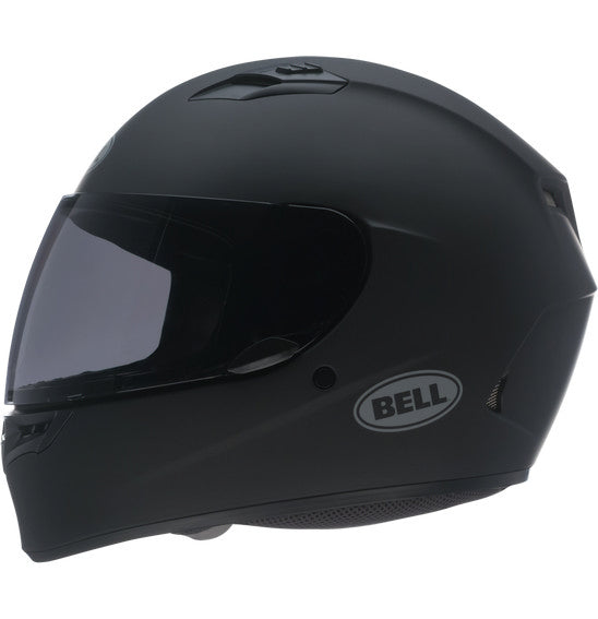 A Bell QUALIFIER Matte Black full-face motorcycle helmet is shown from a side angle, featuring an aerodynamic design with a smooth matte finish and a clear visor. The helmet includes a top vent for airflow, the "Bell" logo on the side, and Multi-Density EPS Liner for enhanced safety.