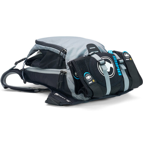 A neatly arranged display of USWE's Patriot 15L MTB Protector Pack highlights its gray backpack with open compartments, black sleek padding, and straps with blue branding. Featuring the CE-certified SAS-TEC protection and an NDM 4-point harness system, it's engineered for high-performance outdoor activities.