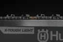 Image of a Husqvarna X-Tough Light 24" Solid bar 3/8" chainsaw bar. The bar is silver with black trim, featuring the Husqvarna logo in the center. Designed for durability, it boasts a replaceable sprocket nose and lightweight construction, with holes for attachment at one end.
