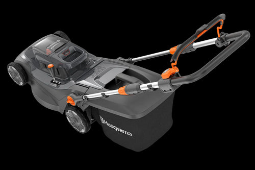 Image of a Husqvarna Aspire™ L34 Lawn Mower (Kit) with an 18V battery. The black mower, accented in orange, features a sleek design and a grass collection bag at the back. With the POWER FOR ALL battery system, its handlebar is adjustable and foldable for easy storage.