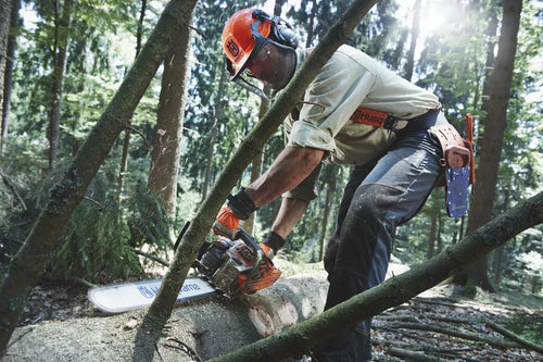 A HUSQVARNA 562XP-20 Chainsaw with an orange and gray body, ideal for forestry and gardens. The chainsaw features a long silver blade marked with "Husqvarna" and "X-Force." The machine has a sturdy handle and appears to be suited for heavy-duty cutting tasks.